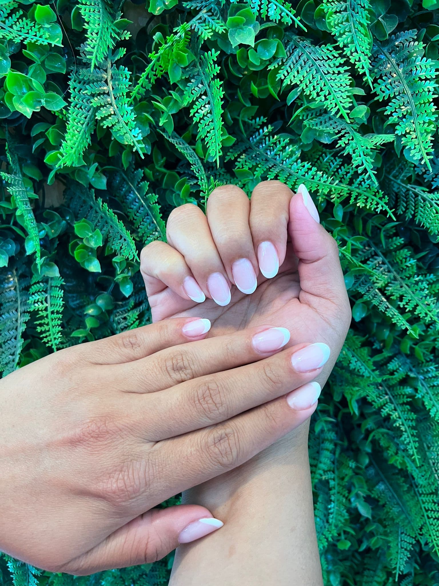 Manicure tradicional em tom claro e natural, mãos entrelaçadas